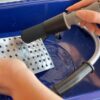 Flow-through brush cleaning metal parts in a parts washer