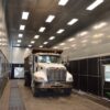 Full-size dump truck parked inside a Kresco drive-in blast room with rubber-lined walls and floor media recovery grating