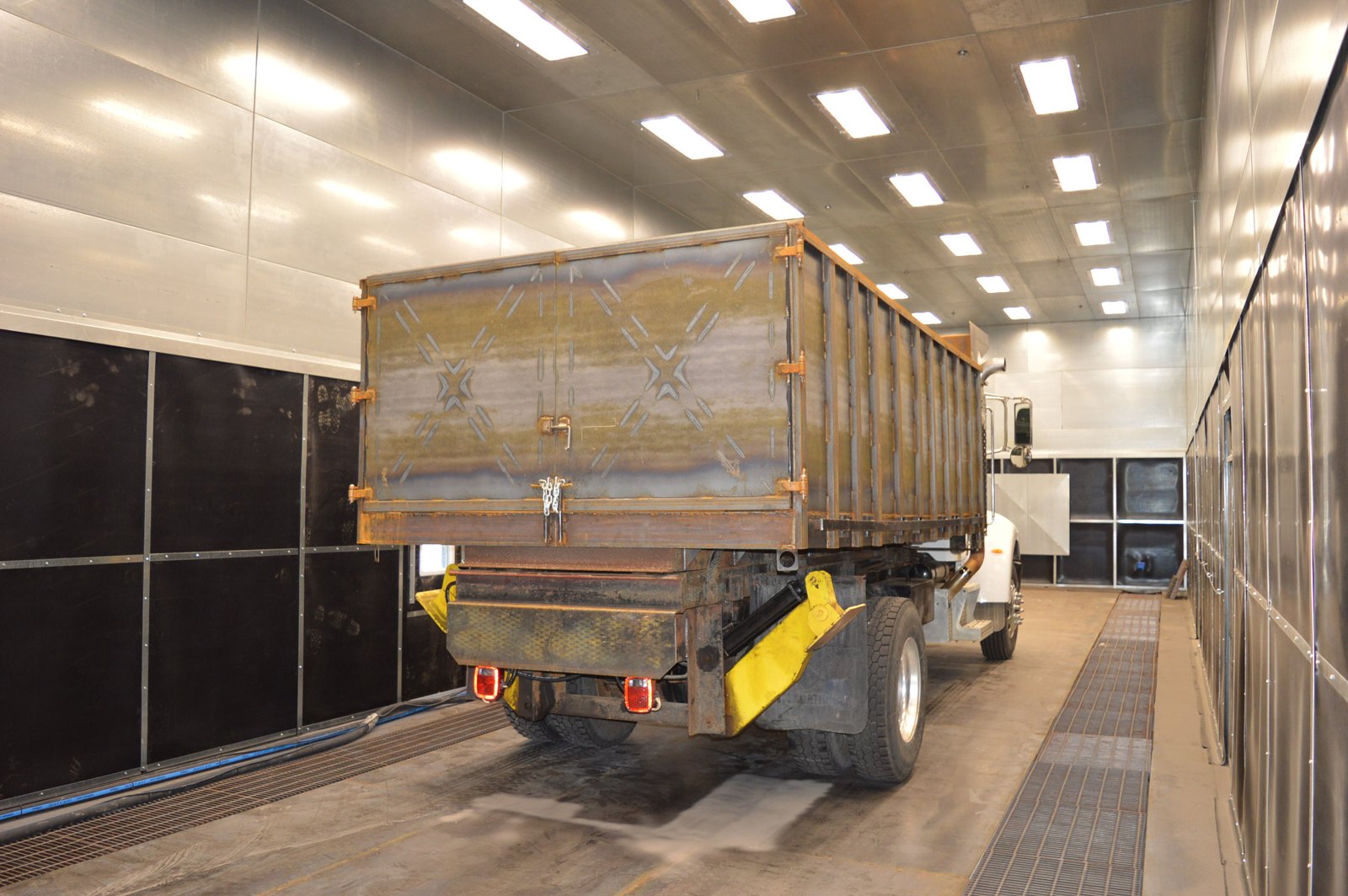 Freshly blasted truck-mounted grain and dump body inside a Kresco blast room, showing bare white metal ready for coating