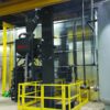 Kresco pneumatic abrasive media recovery system installed beside a blast room: bucket elevator, media classifier and storage hopper, blast pot with safety railing, and air receiver tank