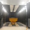 Kresco blast room with full-width doors open, hopper positioned on the grated media recovery floor ready for abrasive blasting